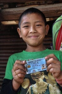 an indigenous lahu hilltribe boy proudly holding up his blue thai ID card