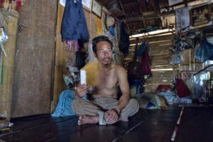 Tior, a Karen Thailand hilltribe man, is sitting on the floor.