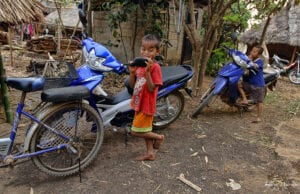 northern thailand hilltribes - jeffrey warner - nam bor noi karen village - development - kids with motorbikes and looking at themselves in the mirror