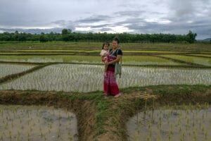 northern thailand hilltribes - jeffrey warner - nam bor noi karen village - karen woman standing in the rice field while holding her child